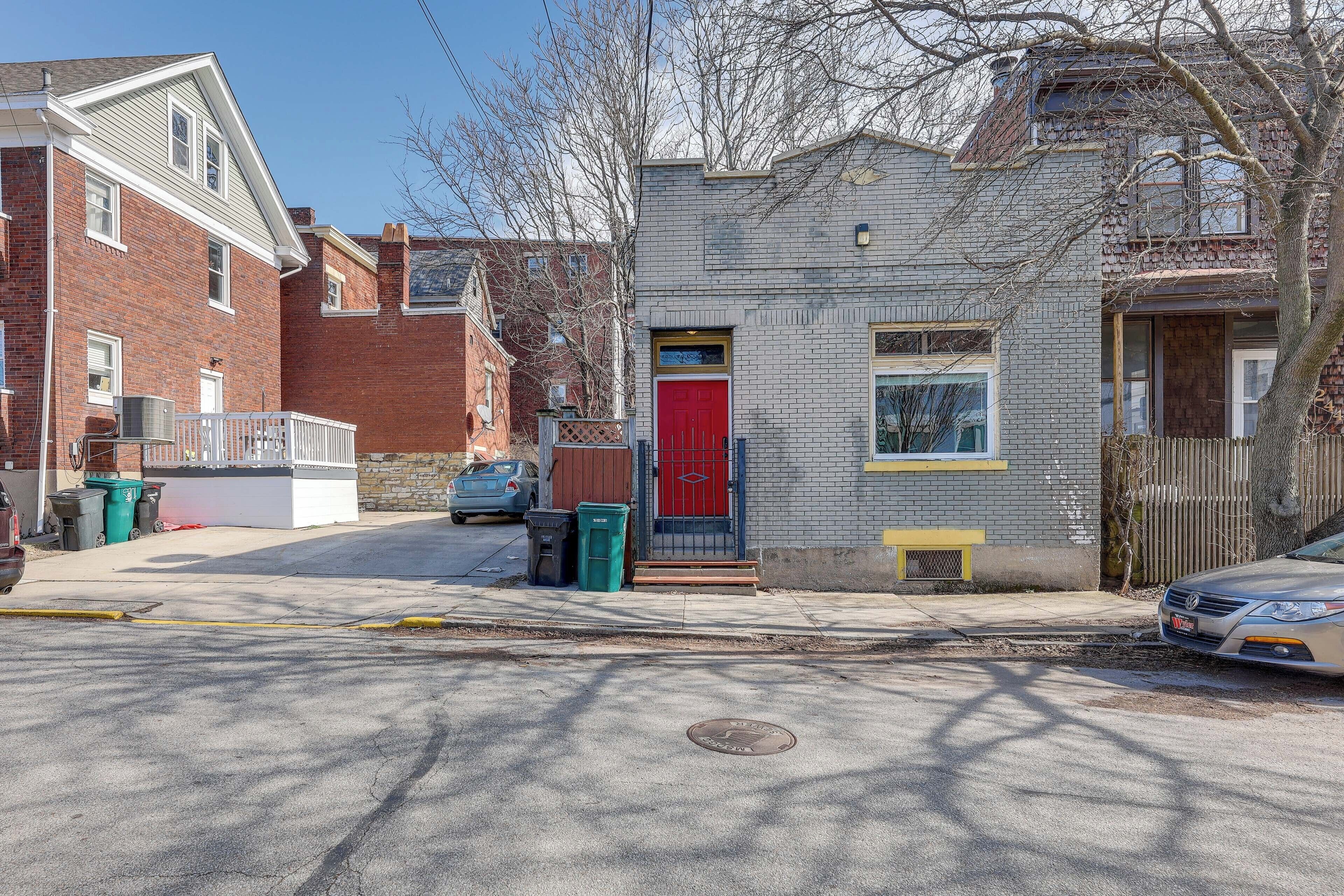 Une rue résidentielle bordée de maisons, avec une porte rouge et une voiture garée.