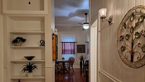 Un couloir comprenant un coin repas, un plancher en bois, des murs blancs et un élément décoratif mural.