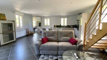 A spacious living area with a sofa, a glass coffee table, and a staircase.