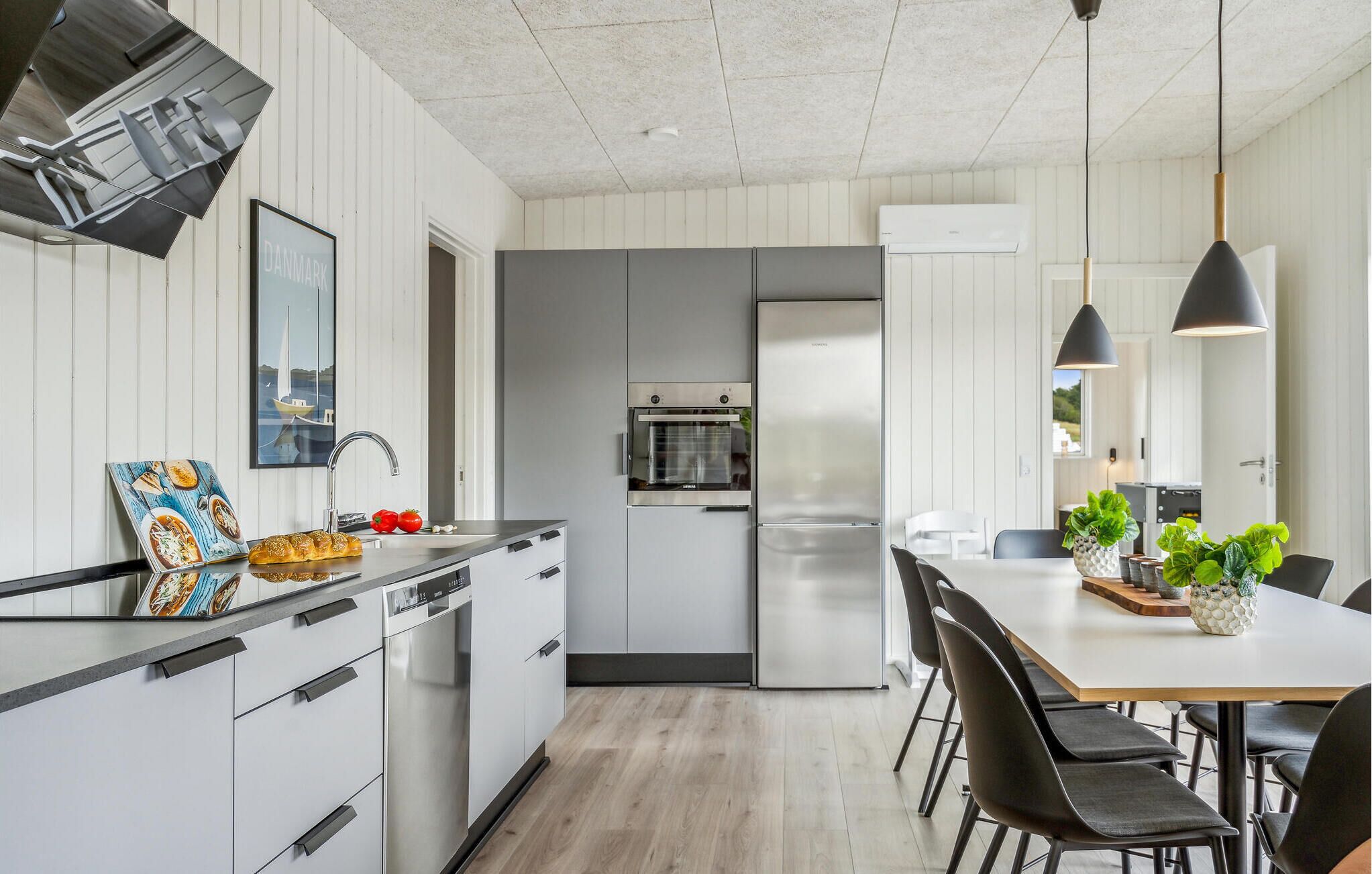 Eine moderne Küche mit Einbauofen, Kühlschrank und Essbereich mit Tisch und Stühlen.