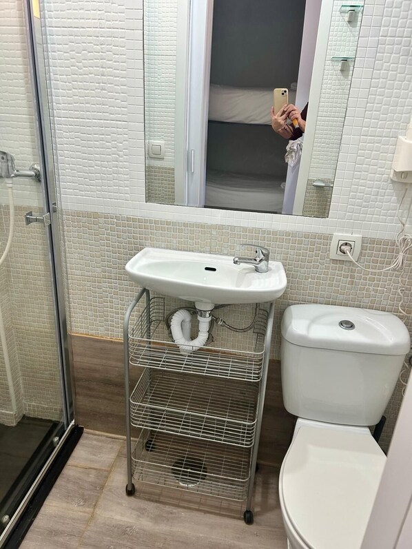 Et badeværelse med en hvid vask, toilet og bruseområde.