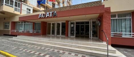 Fachada de hotel roja, con varios balcones e insignias, incluyendo la bandera de la Unión Europea.