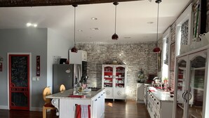 A spacious kitchen with a central island, wooden flooring, and a brick wall. - Eclectic Loft atop Art Studio in the heart of Scott Joplin Land! (Sedalia)