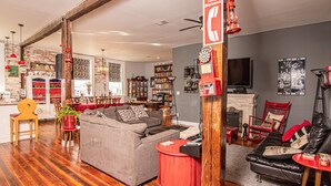 A cozy living room with a grey sofa, a red armchair, and a black leather couch. There is a bookshelf filled with books and a fireplace. - Eclectic Loft atop Art Studio in the heart of Scott Joplin Land! (Sedalia)