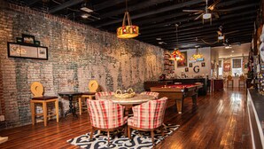 A cozy bar area with a pool table, plaid chairs, and a brick wall. - Eclectic Loft atop Art Studio in the heart of Scott Joplin Land! (Sedalia)