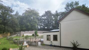 A residential property with a fenced backyard, a gravel patio, and a white building with windows.