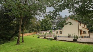 A house with a well-maintained lawn, a wooden fence, and potted plants. - Rudbaxton Water (Haverfordwest)
