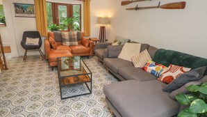 A living room with a sofa, armchairs, a coffee table, patterned floor tiles, a painting, and a window with curtains. - Rudbaxton Water (Haverfordwest)