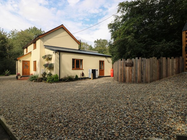 A two-story house with a gravel driveway, wooden fence, and a sign reading "RUBBINGTON WATERS". - Rudbaxton Water (Haverfordwest)