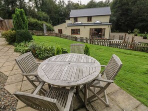 A round wooden table with six chairs in a backyard setting. - Rudbaxton Water (Haverfordwest)