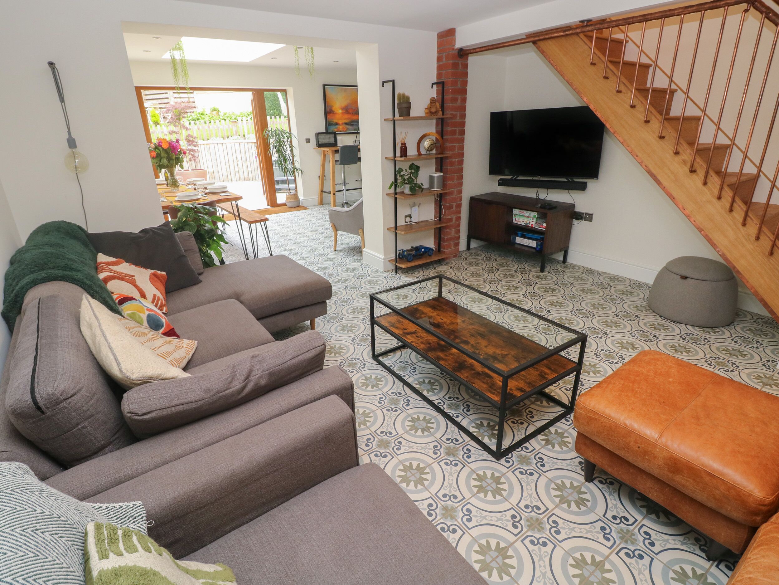 Una sala de estar moderna con sofá, reposapiés, mesa de centro y televisor.