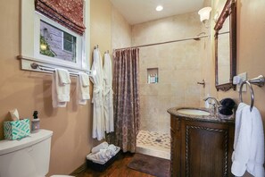 A bathroom with a shower, a toilet, a sink, and a window. - Charming Queen Suite, two person jet tub, downtown (Sturgeon Bay)