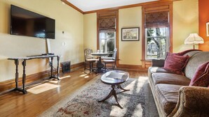 A living room with a flat-screen TV, a dining table with chairs, a sofa, and a patterned rug.