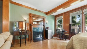 A room with a fireplace, wooden flooring, a desk with a chair, and a bed. - Cozy king Suite, two person jet tub, Downtown! (Sturgeon Bay)