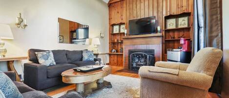 Una sala de estar acogedora con chimenea, televisor y estantería.