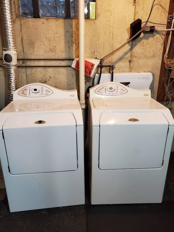 Two white front-loading washing machines in a room with a concrete wall and a window. - Relaxation on the river - Extra Cleaned (Onalaska)