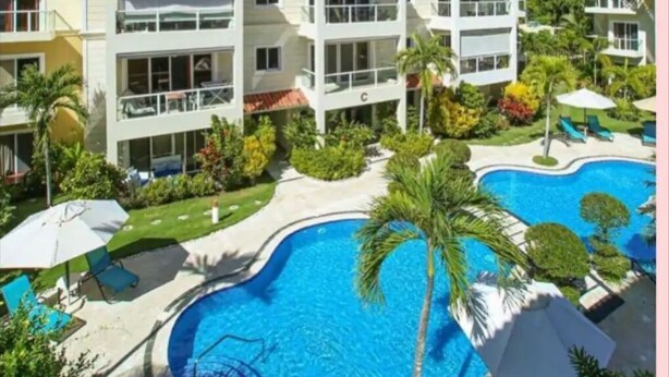 Ett semesterhotell med en swimmingpool, flervåningsbyggnader och utomhusområden med sittplatser.