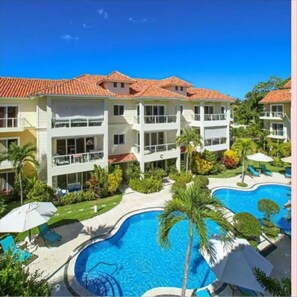 A resort with a swimming pool, multiple-story buildings, and outdoor seating areas.
