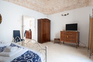 Une chambre à coucher avec un lit, une armoire en bois, une télévision et une petite table.