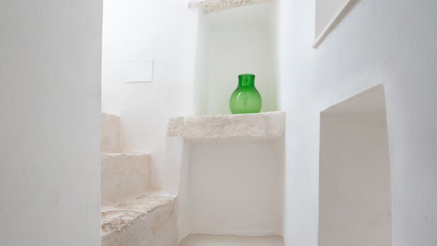 Eine schmale Treppe mit einer grünen Flasche auf einem Regal.