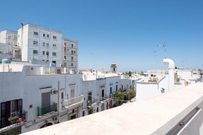 Un immeuble à plusieurs étages doté de balcons, un ciel dégagé et une structure de tuyaux blancs.