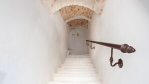 Eine enge Treppe mit weißen Stufen, die zu einer Tür oben führt.