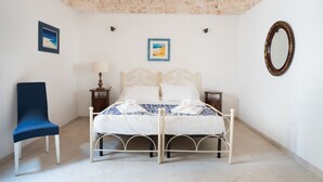 Ein Schlafzimmer mit einem Bett, einem Sessel, einer Lampe und zwei gerahmten Bildern an der Wand.