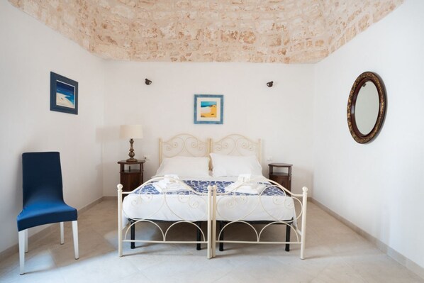 Une chambre à coucher avec un lit, une chaise, une lampe et deux tableaux encadrés accrochés au mur.