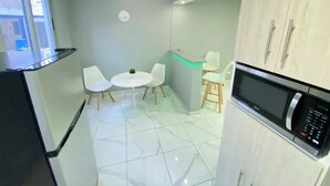 A compact kitchen with a microwave, a small dining table with chairs, a ceiling fan, and a window.