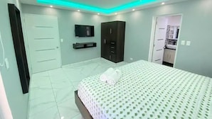 A bedroom with a bed, a wardrobe, a television, and a ceiling fan.