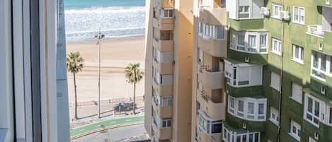 A high-rise building with multiple balconies overlooking a beach.