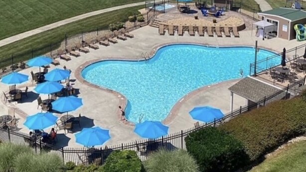 Una piscina con diseño en forma de corazón, rodeada de sillones de descanso y sombrillas.