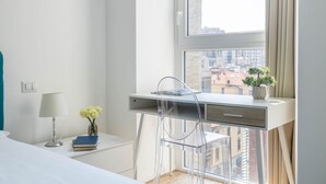 A modern bedroom with a desk, chair, lamp, books, and a vase of flowers. - Hostmate - Milano - Pirelli - Porta Nuova (Milano)