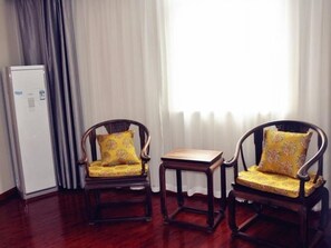 Two wooden chairs with yellow cushions, a small wooden table, and a white refrigerator in a room with wooden flooring and a window with sheer curtains. - Greentree Inn Xuzhou Benteng Avenue Express Hotel (Xuzhou)