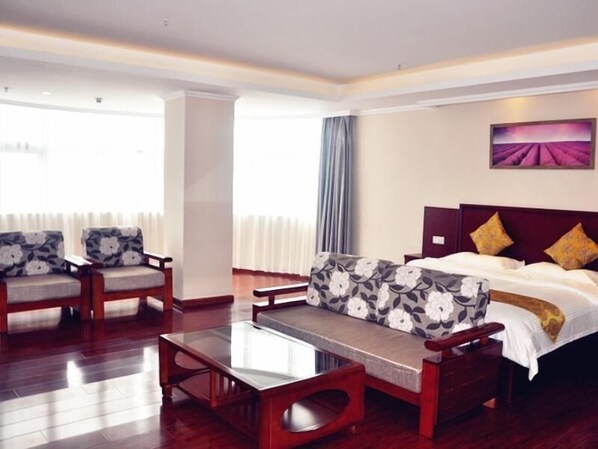 A hotel room with a bed, a sofa, a coffee table, and a chair. - Greentree Inn Xuzhou Benteng Avenue Express Hotel (Xuzhou)
