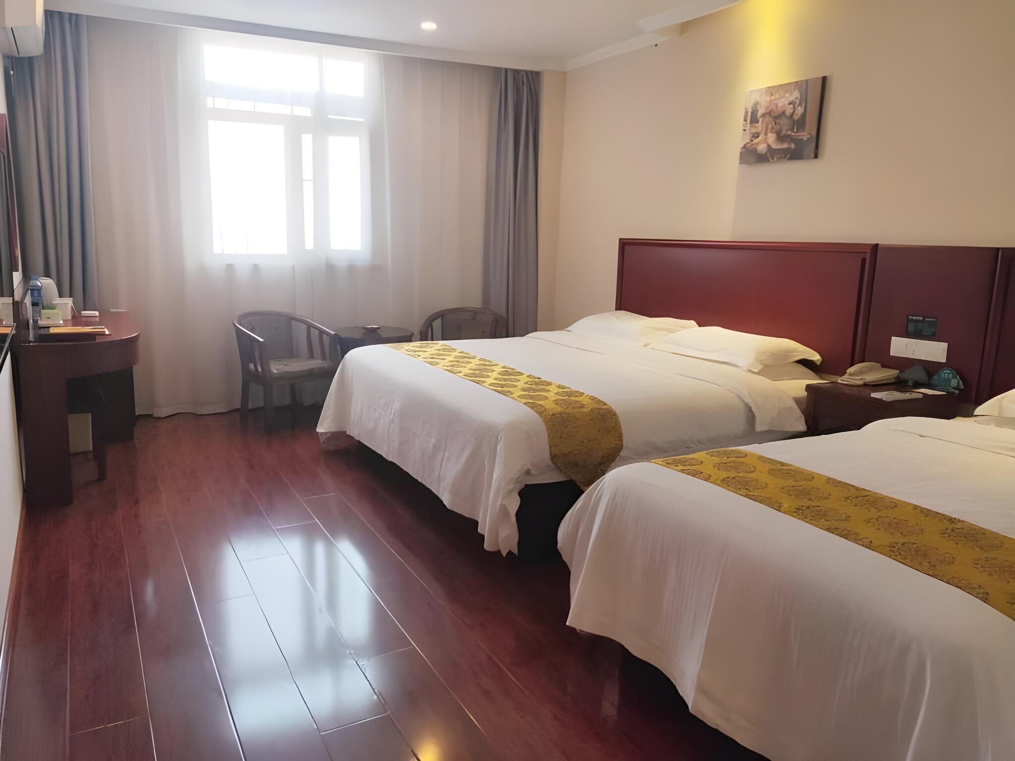 A hotel room with two beds, a desk, a chair, and a window with curtains.