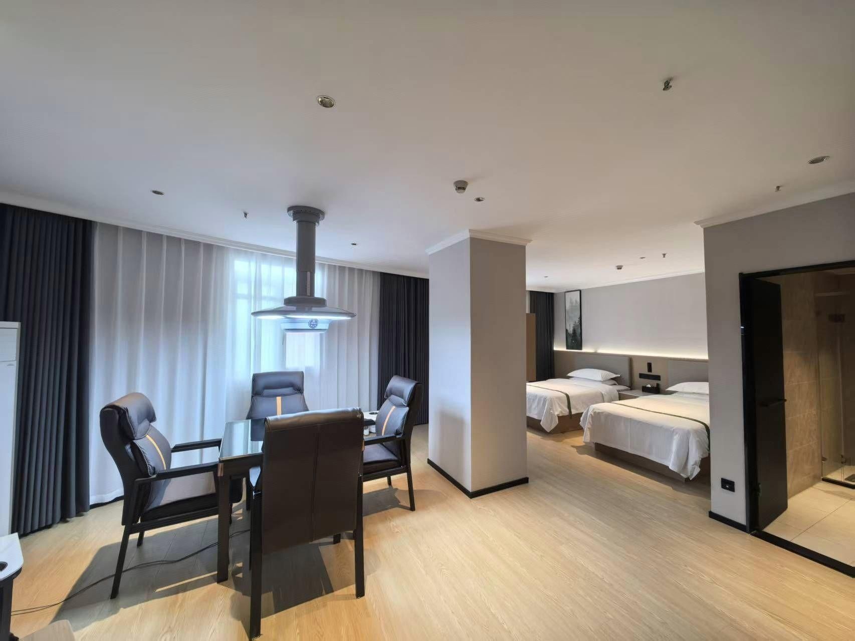 A hotel room with a dining area, two beds, a large window, and a modern design.