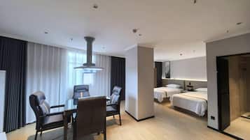 A hotel room with a dining area, two beds, a large window, and a modern design.