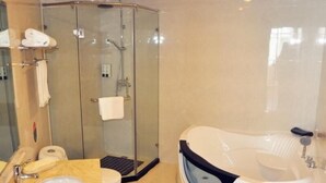 Un baño moderno con ducha envuelta en cristal, una bañera independiente y un tocador de mármol.