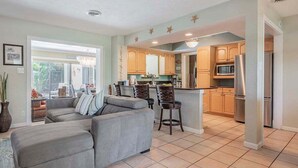 A modern kitchen with a central island, bar stools, and a dining area. - The Edison - Walking Distance to Gulf Course and Edison-Ford Winter Home (Fort Myers)