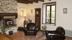 Ein gemütliches Wohnzimmer mit Kamin, Ledersesseln und einem großen Fenster.