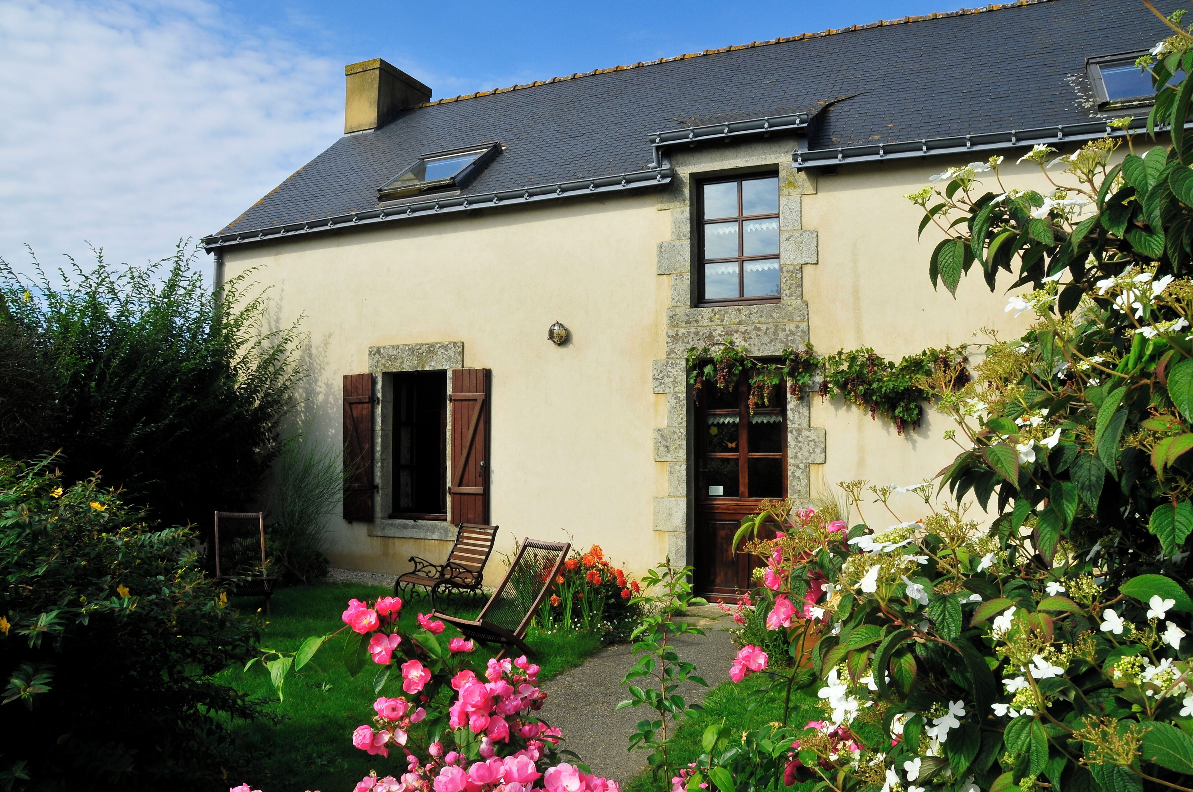 Une maison avec un jardin, un banc et une porte.
