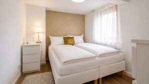 Una camera da letto moderna con un letto matrimoniale, comodini, una lampada e una finestra con tende leggere.