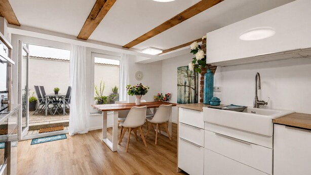 Una cucina moderna con mobili bianchi, un tavolo da pranzo in legno e una grande finestra.