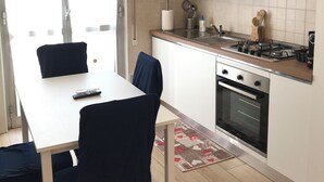 A modern kitchen with white cabinets, a gas stove, an oven, and a dining area with a table and chairs.