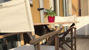 A wooden chair with a white cushion and a table with a red pot on it.