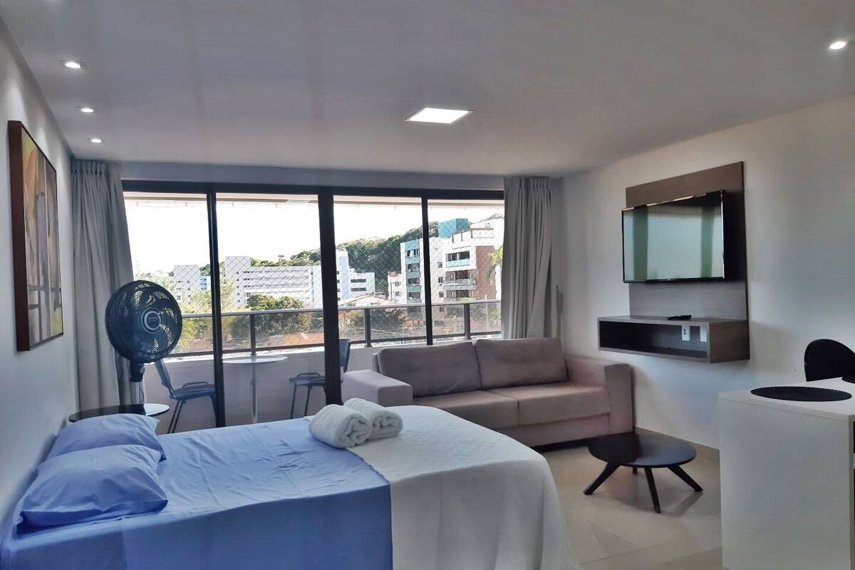 Una habitación de hotel moderna con cama, sofá, escritorio y televisor.