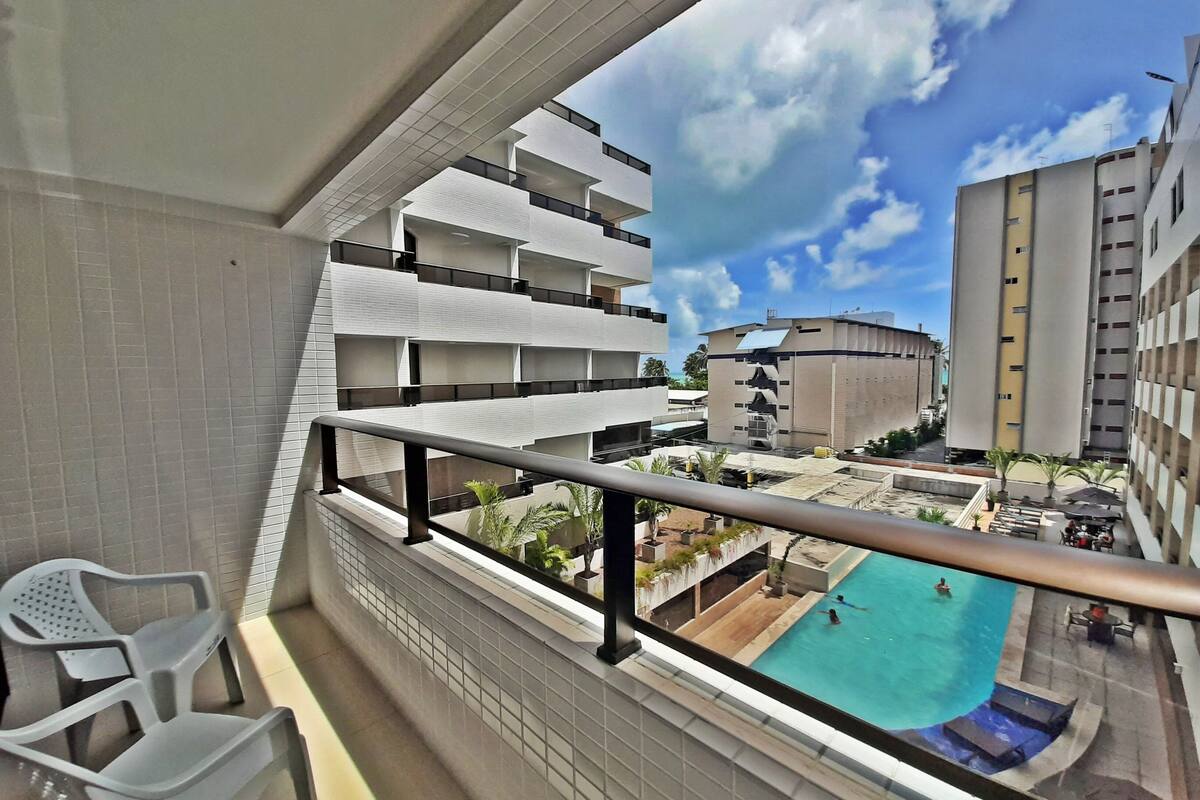 Un balcón con vista a una piscina y edificios cercanos.