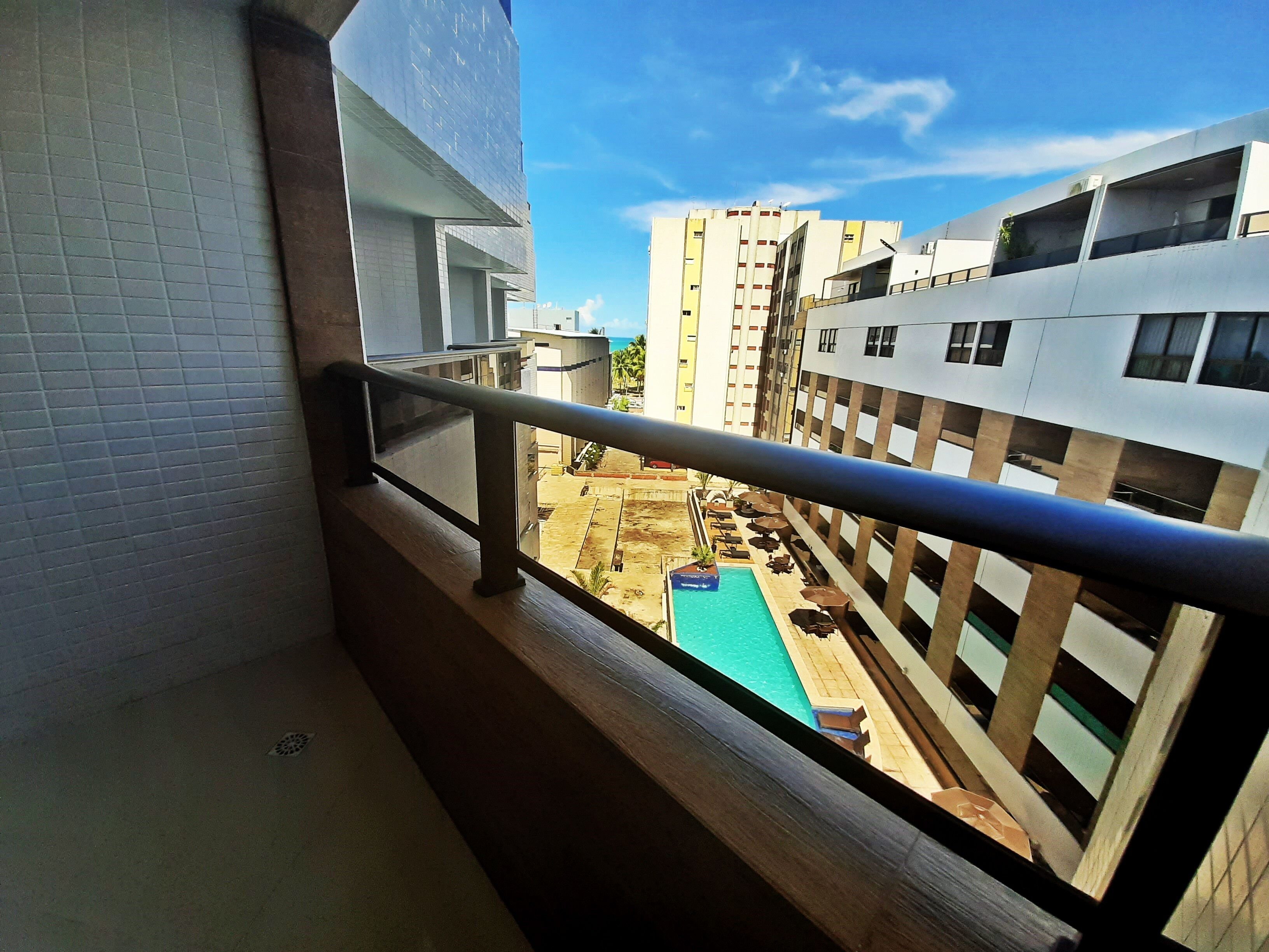 A balcony with a view of a swimming pool and adjacent buildings.