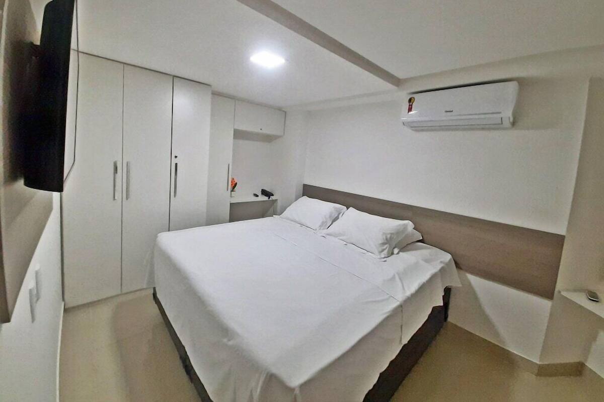 Habitación de hotel con cama, armario y aire acondicionado.